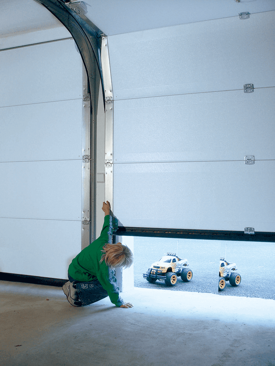 Child playing with the frame of a half-opened garage door